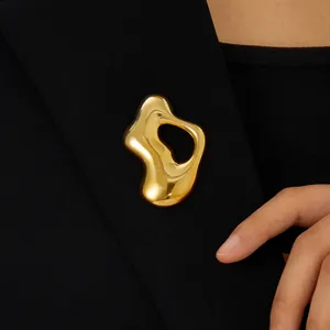 Detail shot of an organic-shaped gold plated stainless steel brooch on a black blazer.