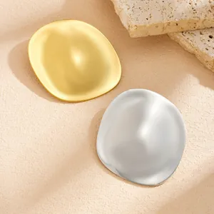 Close-up of gold and silver irregular smooth metallic brooches on textured stone background