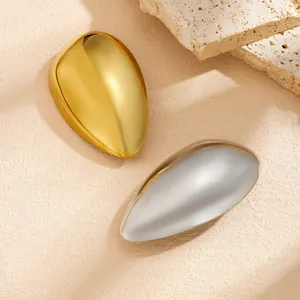 Detailed macro view of high-polished gold and silver teardrop pins on beige stone
