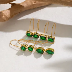Vista macro de pendientes bañados en oro con circonitas verde esmeralda en varias formas