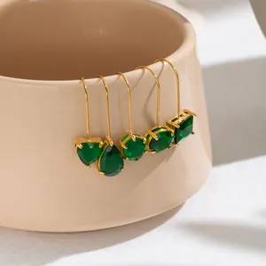 Detalle de varias formas de pendientes de gancho en circón verde y acero chapado en oro 18K.