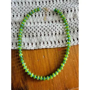 Close-up detail of handmade green abacus stone bead necklace with blue spacer beads.