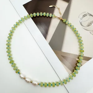 Detailed view of a green natural stone necklace with three baroque pearls on a white background.