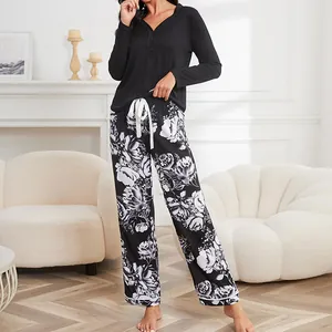 Two-piece women's pajama set featuring black long-sleeve top and floral botanical print pants