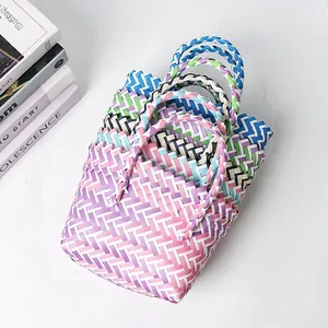 Detalle de bolsos de mano de plástico tejido a mano de colores apilados.