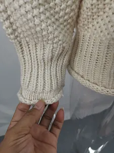 Macro detail of white chunky knit sweater showing ribbing texture on the cuff