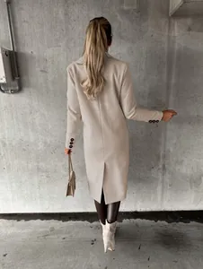 Detailed back view of a minimalist beige long wool coat with a back slit and buttoned cuffs
