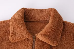 Détail macro d'une veste en polaire teddy marron avec col chaud et texture de fermeture