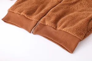Détail d'une veste en polaire peluche marron avec fermeture éclair et ourlet.