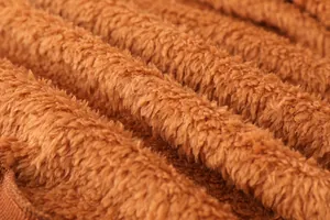 Gros plan sur la texture du tissu polaire teddy marron doux pour manteau d'hiver