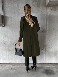 Elegant back view of a woman wearing a dark olive green long wool coat in a modern setting.