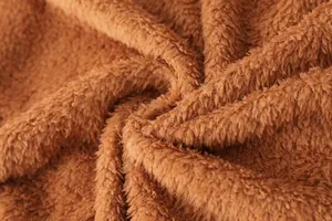 Gros plan sur la texture du tissu polaire teddy marron doux pour manteau d'hiver