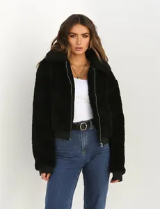 Femme portant une veste polaire teddy noire confortable avec fermeture éclair et col.