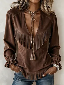 Détail d'un haut marron vintage en daim à col en V avec des franges et des poignets à volants.