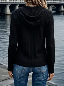 Back view of a black long-sleeve ribbed hooded top for women in casual outdoor setting.