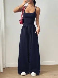 Stilvoller dunkelblauer Neckholder-Jumpsuit mit weitem Bein, roter Tasche und Sneakern