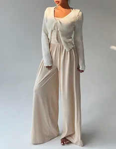Detailansicht eines beigen Jumpsuits mit weitem Bein und weißem Strick-Cardigan für Damen