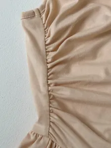 Nahaufnahme des gerafften Seitennaht-Details an einem weichen beigen Sommer-Jumpsuit