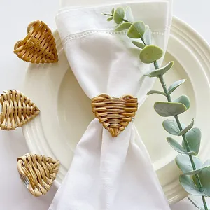 Elegante portatovagliolo in rattan intrecciato a cuore su un tovagliolo bianco di lino