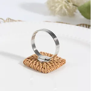 Dettaglio macro della base quadrata in rattan intrecciato con portatovagliolo in metallo argento