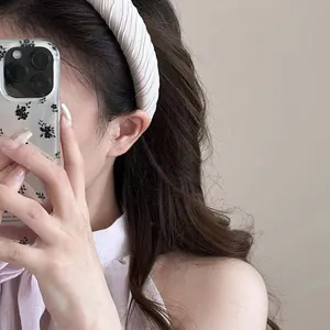 Close-up detail of a cream-colored pleated sponge headband for a minimalist look.