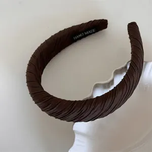 Detailed macro shot of a brown ruched fabric sponge headband with handmade label inside