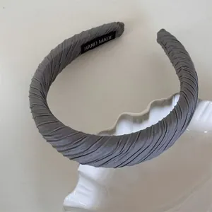 Close-up of a grey pleated sponge headband showing 'HAND MADE' interior label detail.