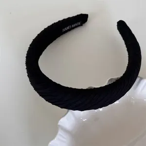 Close-up detail of a black pleated sponge headband featuring a handmade inner label
