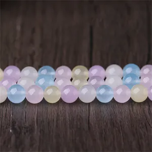 Gros plan de perles rondes en calcédoine morganite colorées sur fond de bois.