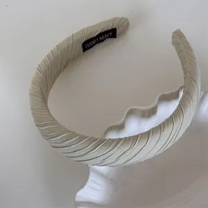 Detailed close-up of a pleated Maillard-colored sponge headband on a display stand