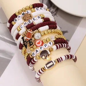 Detalle de pulseras heishi de arcilla burdeos y blancas con dijes de fútbol americano.
