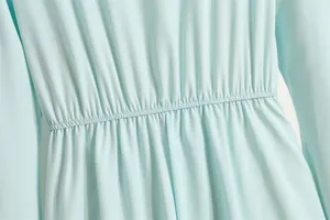 Nahaufnahme der elastischen hohen Taille und der feinen Plisseedetails am hellblauen Chiffonkleid.