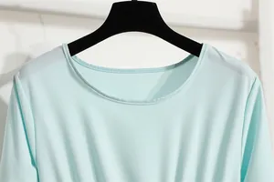 Detailansicht des Rundhalsausschnitts eines mintgrünen Chiffonkleides mit Stoffstruktur.