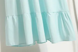 Makroansicht eines hellblauen Chiffonkleides mit zartem Volantsaum und fließendem Stoff