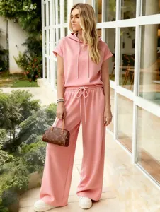 Lifestyle detail of a woman wearing a pink short-sleeve hoodie and wide-leg pants
