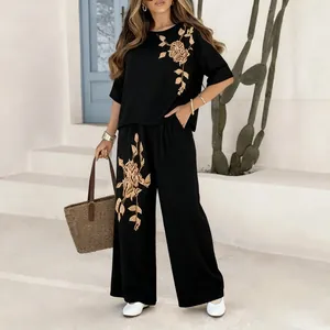 Full body view of a woman wearing a black cotton linen set with gold rose embroidery