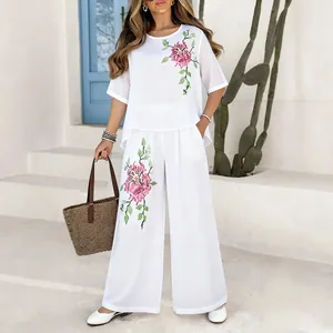 Elegant white cotton linen two-piece set with floral embroidery and wide-leg pants.