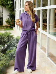 Full view of a woman in purple short-sleeve hoodie and matching wide-leg trousers