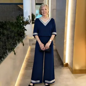 Ensemble deux pièces bleu marine élégant avec col en V, bordure argentée et pantalon large chic.