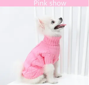 Chien blanc portant un pull en tricot rose à col roulé chaud dans un décor de studio.