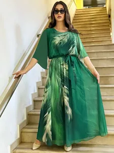 Vista intera di un abito lungo verde con stampa a piume indossato da una modella su scale