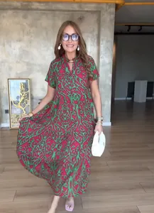 Model draagt een levendige rood-groen bedrukte bohemian maxi-jurk in een studio