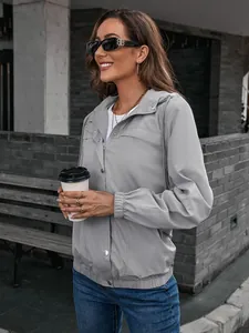 Detailansicht einer grauen Damen-Windjacke mit Kapuze in einer urbanen Umgebung