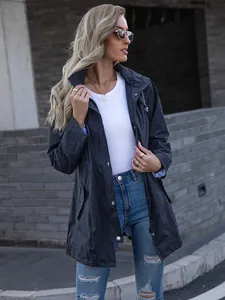 Detailed view of a women's navy blue mid-length hooded raincoat worn by a model outdoors