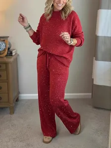Model wearing a festive red sparkling two-piece loungewear sweatshirt and wide-leg pant set.