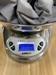 Detail view of the lightweight outdoor jacket being weighed on a digital scale at 151.8g.