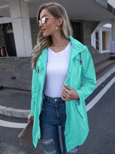 Fashionable women's mid-length mint green hooded rain jacket in an urban street setting