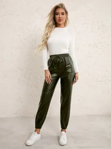 Full body shot of model wearing dark green PU leather joggers with elastic waist and white top