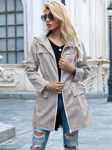 Donna con giacca antipioggia grigia con cappuccio e vita con coulisse all'aperto