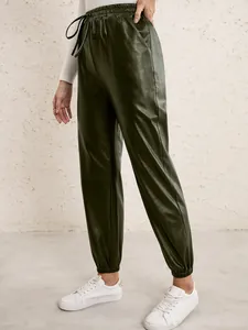 Detailed view of dark olive green faux leather joggers featuring an elastic waistband